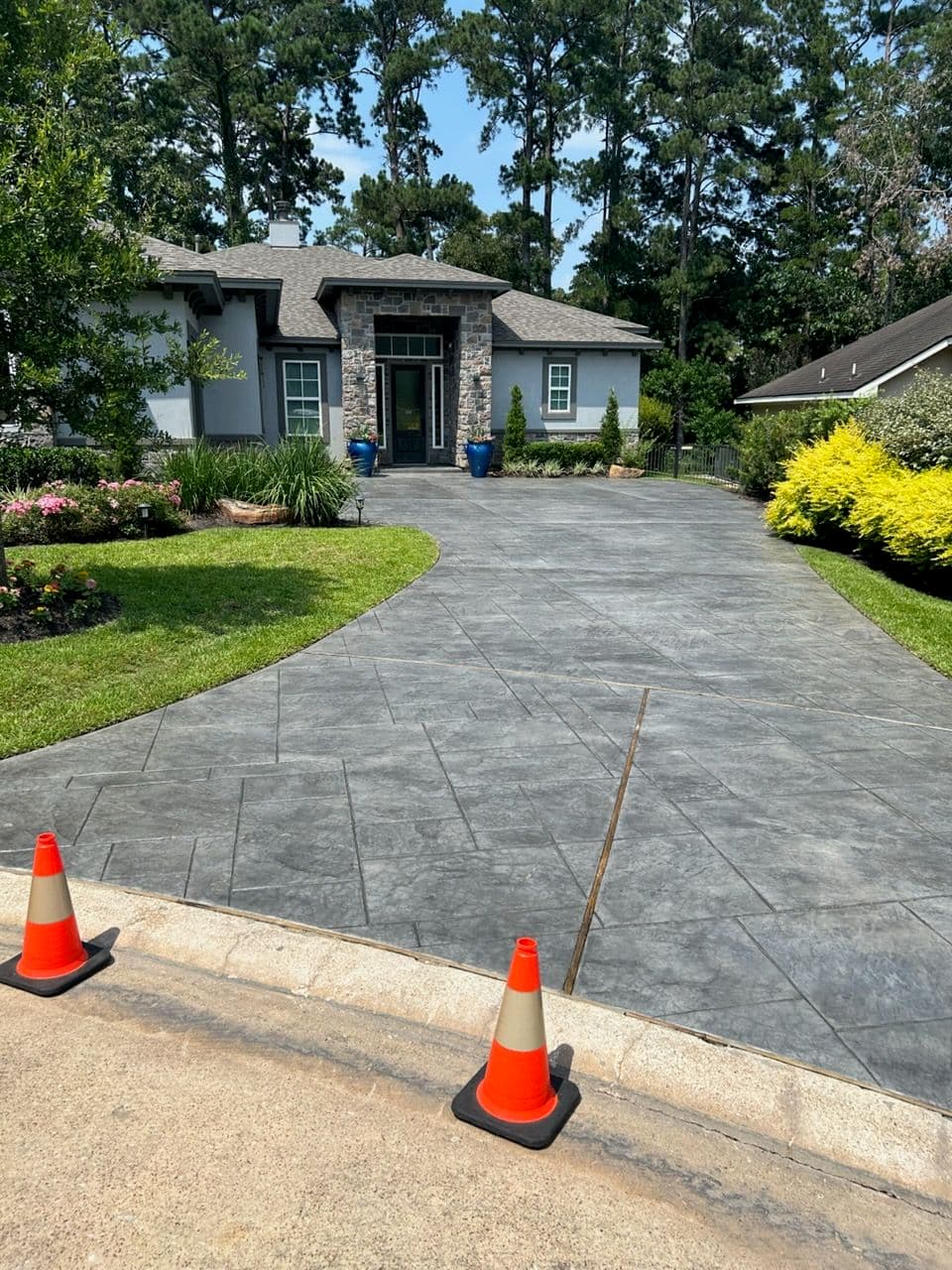 Stylish home entrance with decorative landscaping and a stamped concrete driveway.